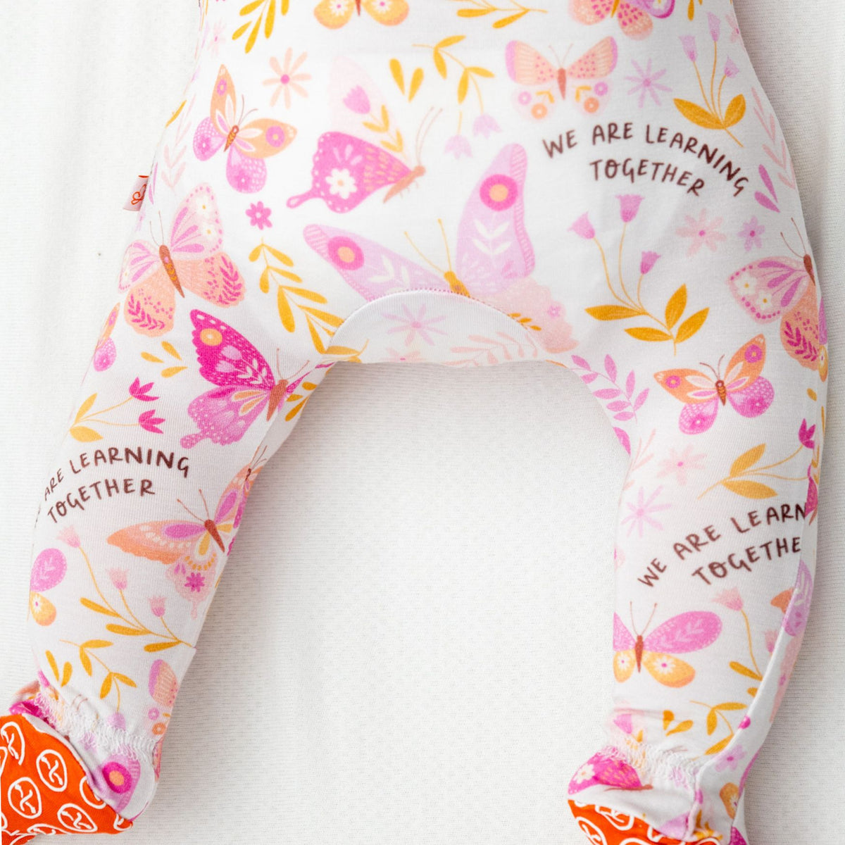 Baby wearing zippered bamboo footie pajamas with hand-illustrated print