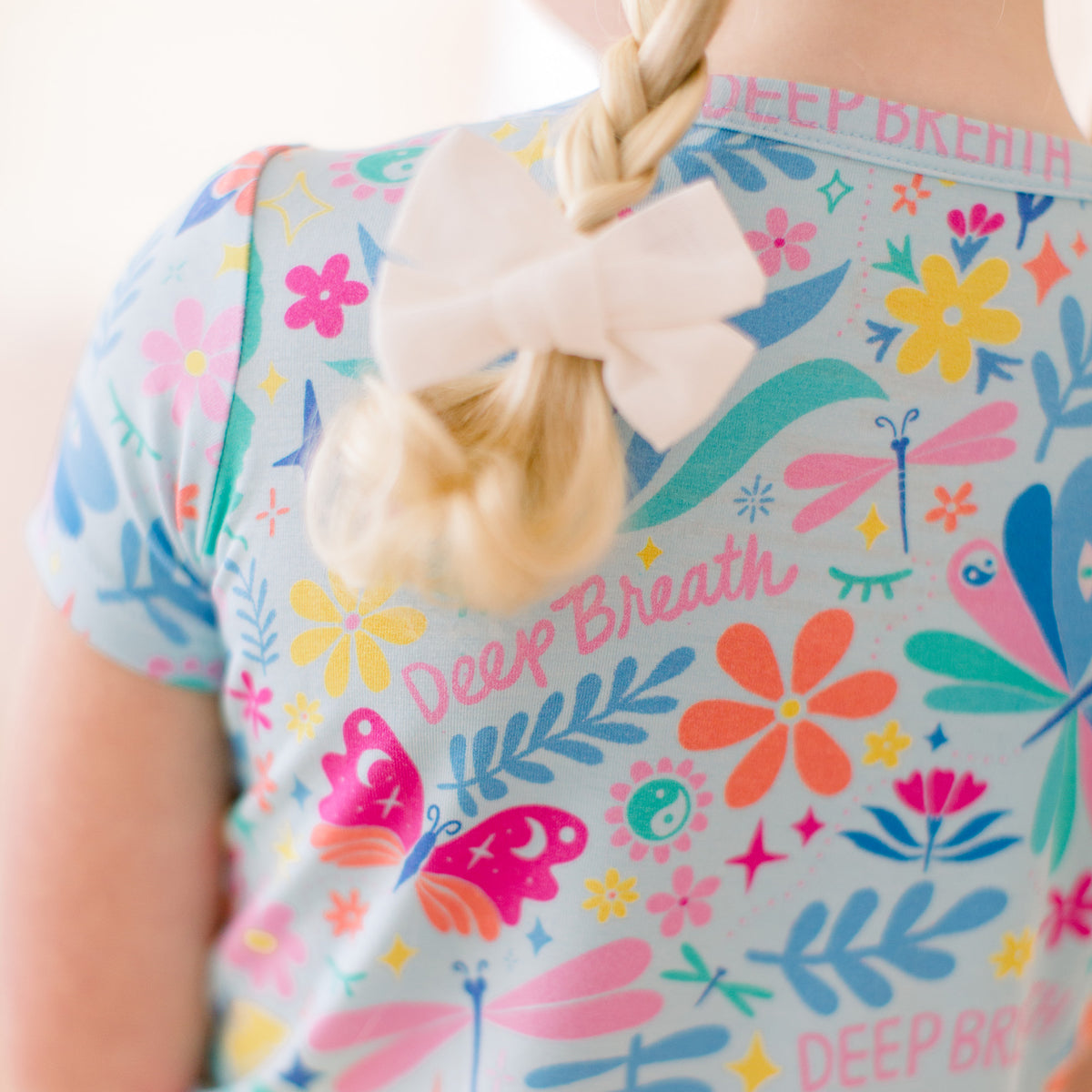 Baby wearing blue and pink Deep Breath floral bamboo pajamas with lotus flowers and butterflies