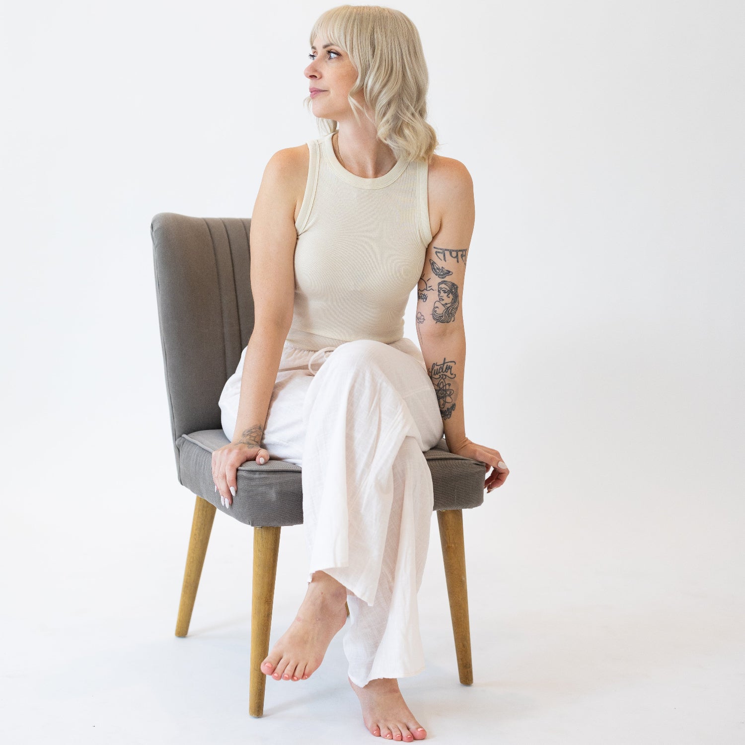 Founder of Raising Mama, Megan Stander, sitting on a chair wearing a white outfit against a plain background